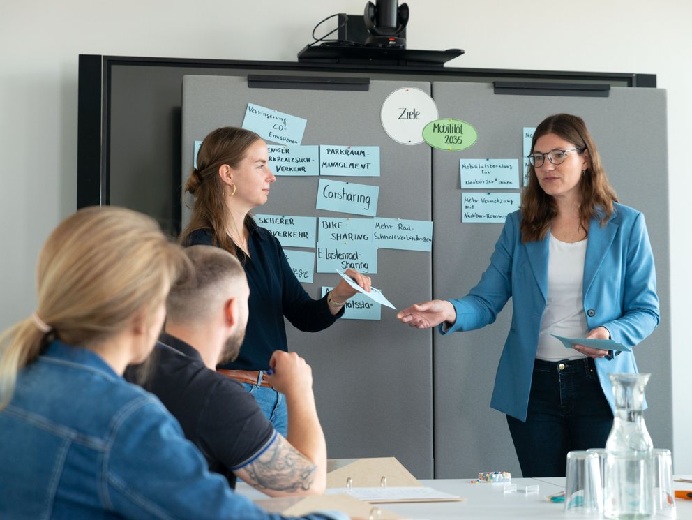 Eine Personengruppe vor einer beschrifteten Stellwand